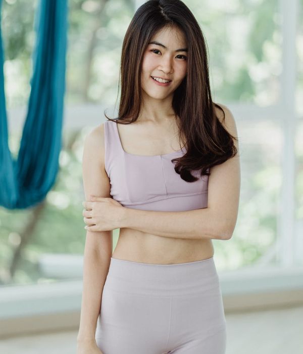 Woman in comfortable sportswear smiling during a light exercise routine indoors.